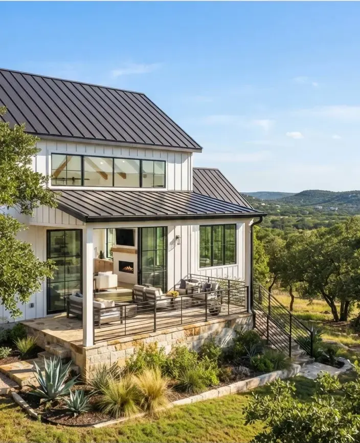 Contemporary farmhouse residence on Fitzhugh Road with standing seam metal roofing, white board and batten siding, sunlit floor-to-ceiling glass,…