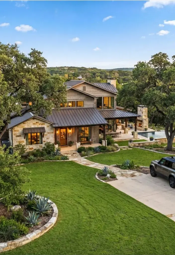 Warm rustic contemporary custom estate in Arrowhead Pass with native Texas stone, metal standing seam accents, and lush manicured lawn framed by…